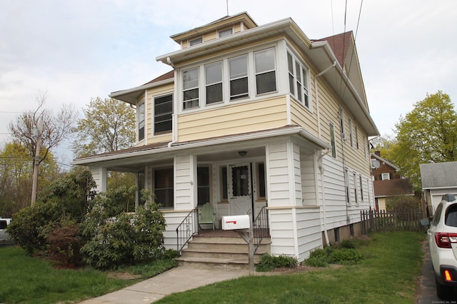 american foursquare style home featuring a front yard and covered porch