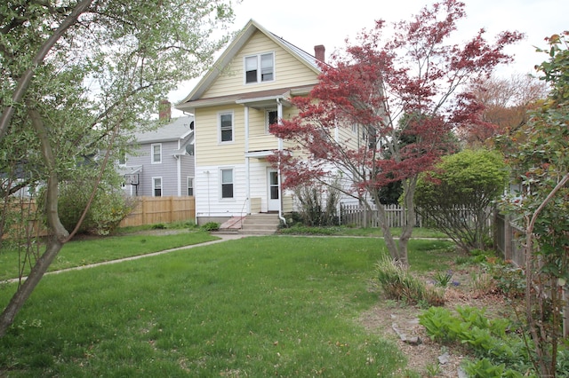 back of property featuring a chimney, fence, and a yard