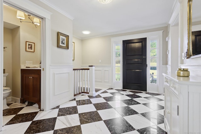 foyer featuring a decorative wall, wainscoting, and crown molding