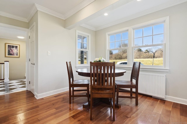 dining room featuring hardwood / wood-style floors, crown molding, radiator heating unit, and baseboards