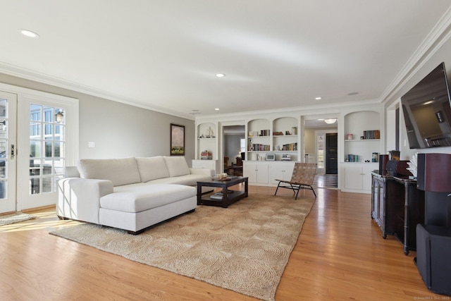 living area featuring light wood-style floors, built in shelves, french doors, and ornamental molding