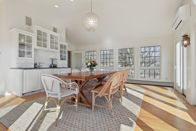 dining space featuring light wood finished floors, a wall mounted AC, high vaulted ceiling, and plenty of natural light