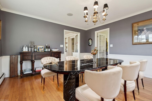 dining area with crown molding, wainscoting, a chandelier, and hardwood / wood-style flooring