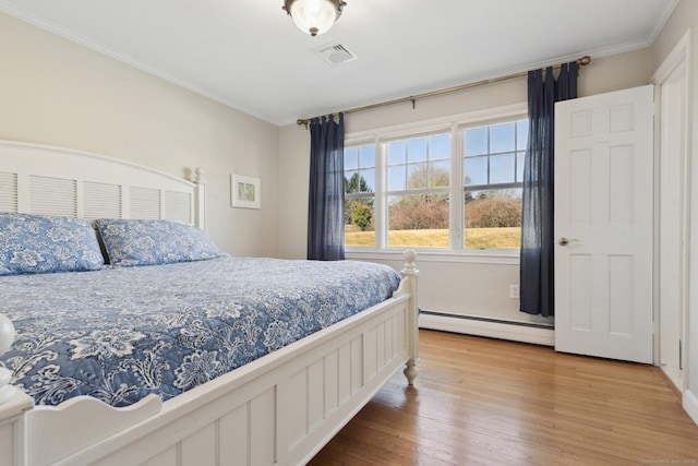 bedroom with crown molding, visible vents, a baseboard radiator, and hardwood / wood-style flooring
