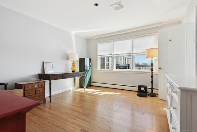 interior space with baseboard heating, light wood-style floors, crown molding, and visible vents