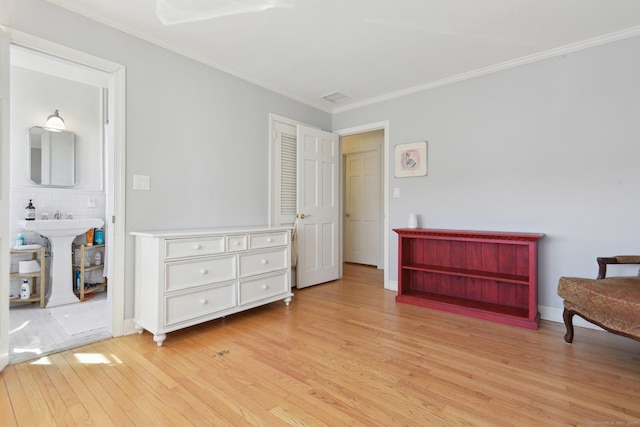 bedroom featuring light wood-style flooring, a sink, crown molding, and visible vents