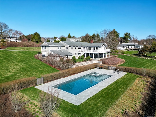 rear view of property featuring a patio area, a fenced in pool, fence, and a lawn