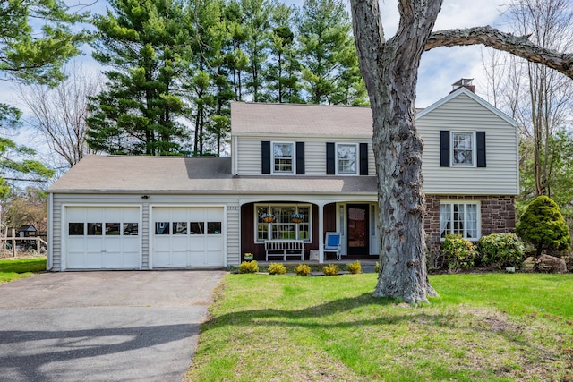 view of front of property featuring a front yard, covered porch, a garage, and aphalt driveway