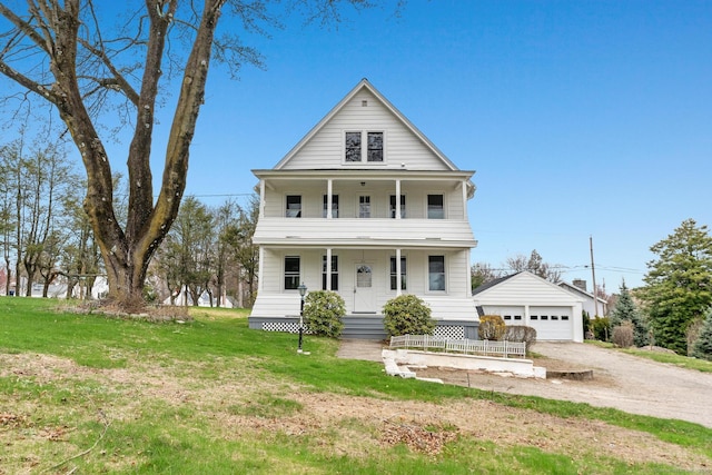 view of front of home featuring a front yard, a balcony, a detached garage, and covered porch