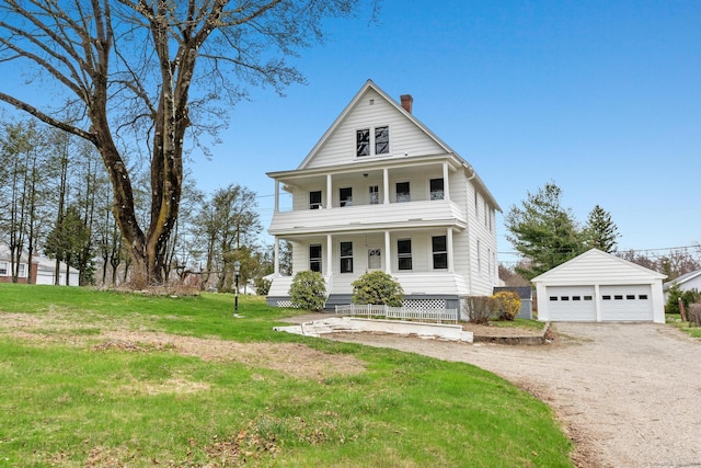 view of front of home featuring a balcony, a detached garage, a front lawn, an outbuilding, and covered porch