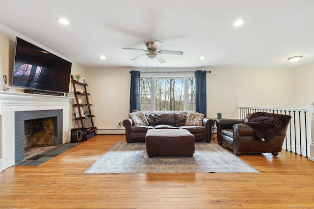 living room with a ceiling fan, wood finished floors, recessed lighting, and baseboard heating