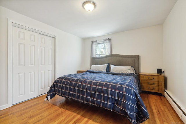 bedroom featuring baseboard heating, wood finished floors, and a closet
