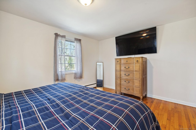 bedroom featuring a baseboard radiator, wood finished floors, and baseboards