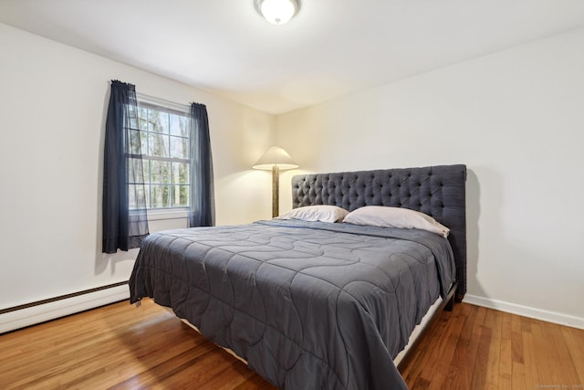 bedroom featuring baseboard heating, baseboards, and wood finished floors