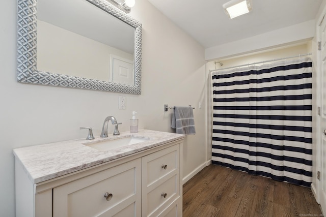 bathroom with baseboards, vanity, wood finished floors, and curtained shower