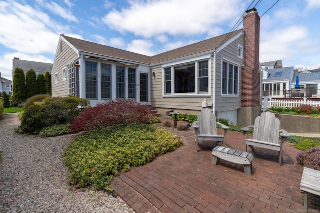 rear view of property featuring fence, a patio, a chimney, and an attached garage