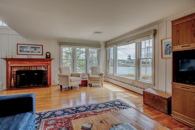 living area with visible vents, wood finished floors, baseboard heating, and a fireplace