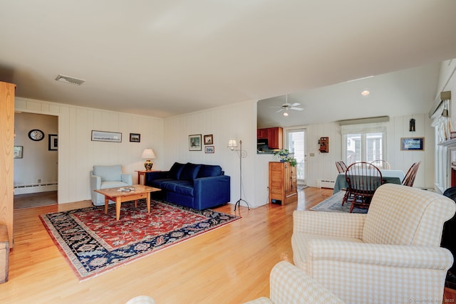 living area featuring light wood-type flooring, a ceiling fan, baseboard heating, and visible vents