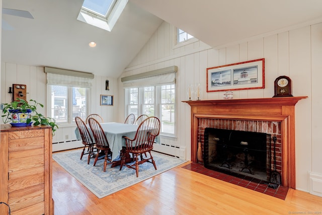dining space featuring plenty of natural light, a brick fireplace, and wood finished floors