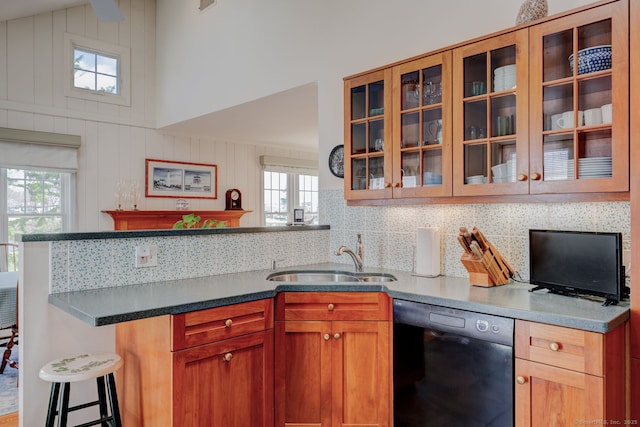 kitchen featuring a sink, a peninsula, black dishwasher, and a wealth of natural light