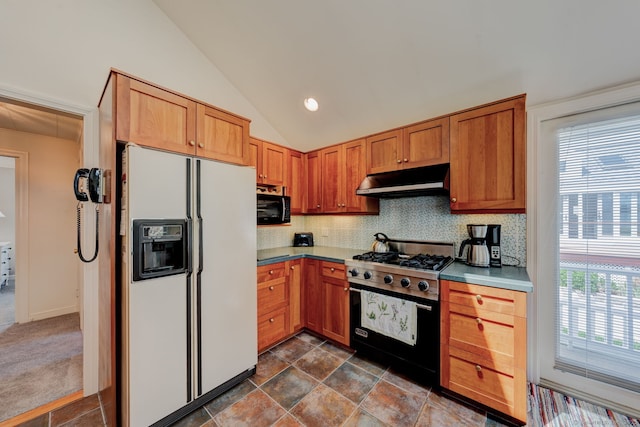 kitchen with decorative backsplash, white refrigerator with ice dispenser, vaulted ceiling, stainless steel stove, and under cabinet range hood