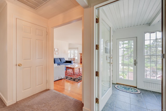 doorway featuring plenty of natural light, ornamental molding, carpet, and visible vents
