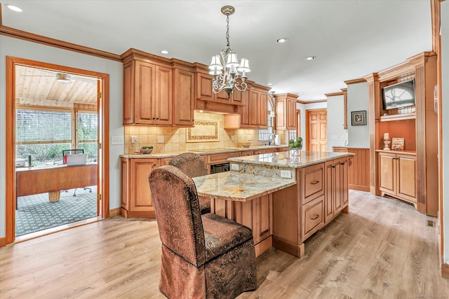 70 Cali Dr, Shelton, CT 06484 - kitchen with light wood finished floors, a notable chandelier, decorative backsplash, light stone countertops, and a kitchen island