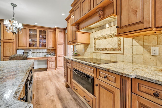 70 Cali Dr, Shelton, CT 06484 - kitchen with brown cabinetry, a warming drawer, black electric stovetop, an inviting chandelier, and backsplash