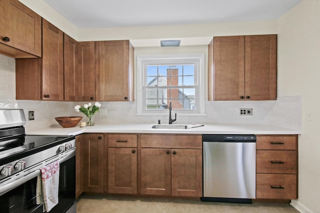 kitchen featuring tasteful backsplash, stainless steel appliances, light countertops, and a sink