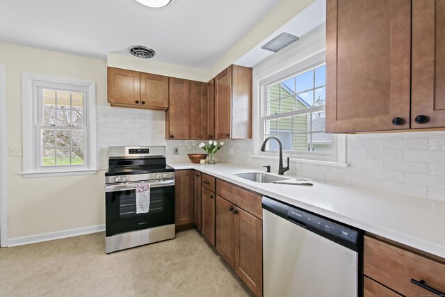 kitchen featuring stainless steel appliances, light countertops, visible vents, a sink, and decorative backsplash