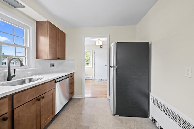 kitchen with stainless steel appliances, light countertops, a sink, and brown cabinetry