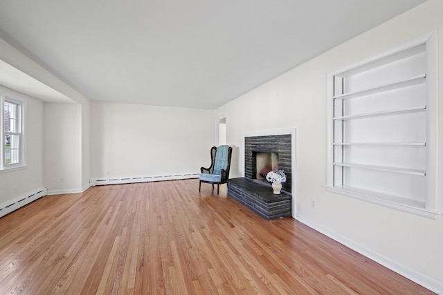 unfurnished room with baseboards, light wood-style floors, built in shelves, baseboard heating, and a stone fireplace