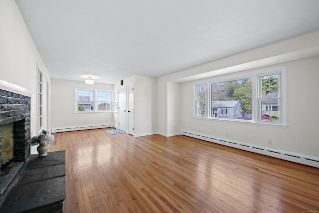 unfurnished living room with baseboards, wood finished floors, a brick fireplace, and baseboard heating