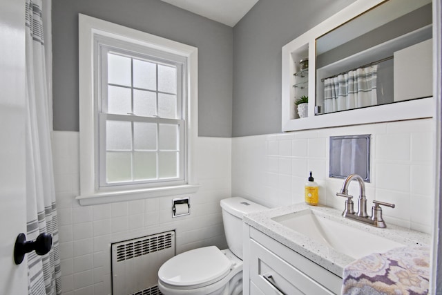 full bath featuring radiator heating unit, vanity, tile walls, a wainscoted wall, and toilet