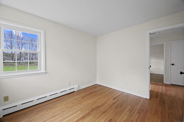 unfurnished room featuring hardwood / wood-style floors, baseboards, and a baseboard radiator