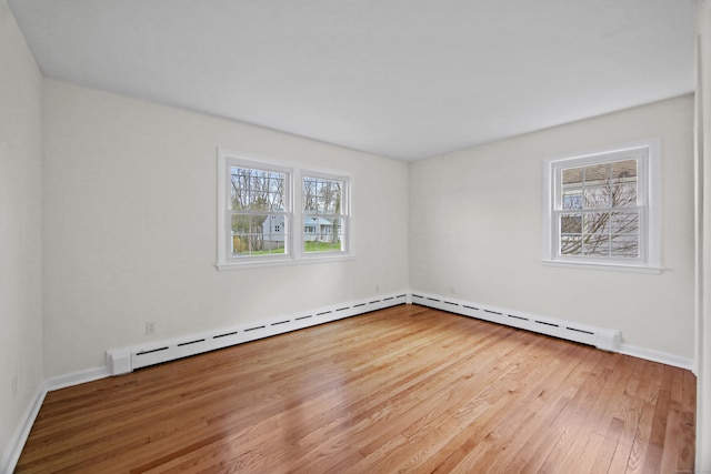 empty room featuring baseboards, a baseboard radiator, and wood-type flooring