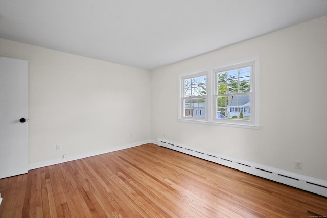 spare room featuring baseboards, wood finished floors, and a baseboard radiator