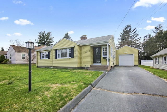 view of front of home featuring a chimney, driveway, an outbuilding, a detached garage, and a front yard