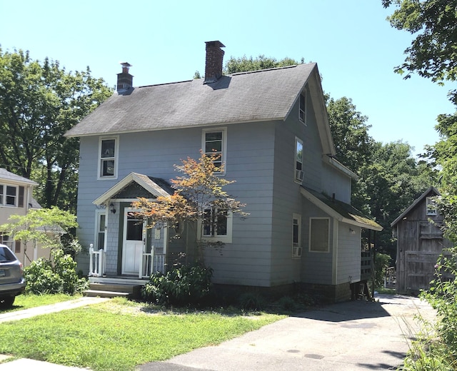 colonial inspired home with fence, roof with shingles, a chimney, and a front lawn