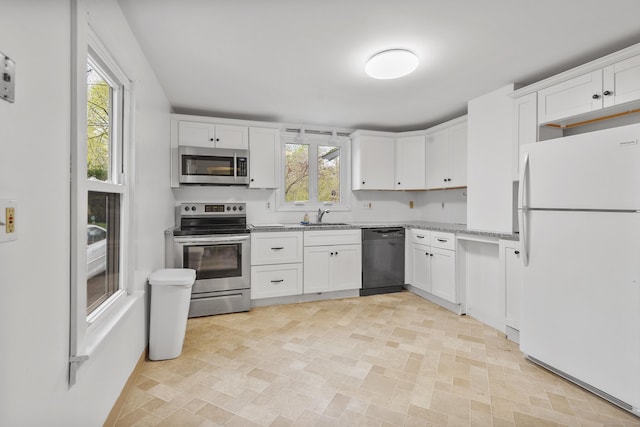kitchen with white cabinetry, appliances with stainless steel finishes, a sink, and light stone counters