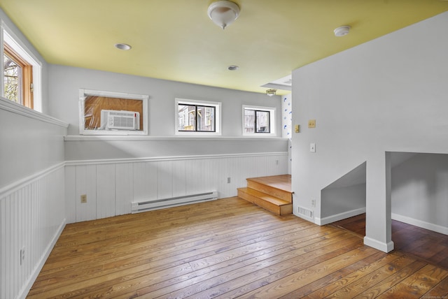 interior space featuring a baseboard radiator, cooling unit, wainscoting, and hardwood / wood-style floors