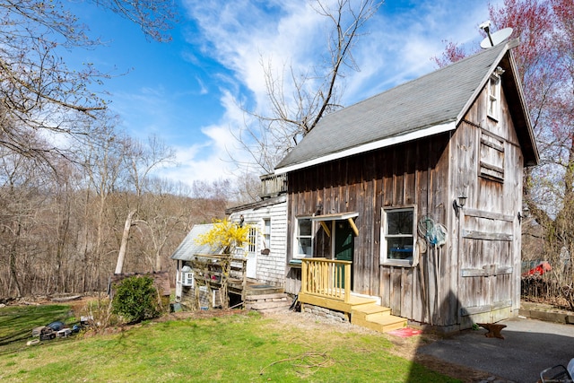 exterior space featuring a lawn, an outbuilding, and roof with shingles