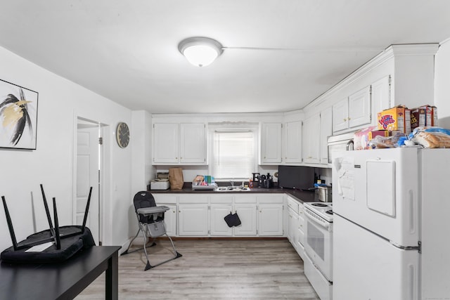 kitchen featuring white appliances, light wood-style flooring, dark countertops, white cabinets, and a sink