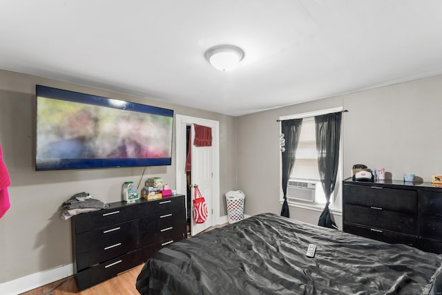 bedroom featuring light wood-style flooring, cooling unit, and baseboards
