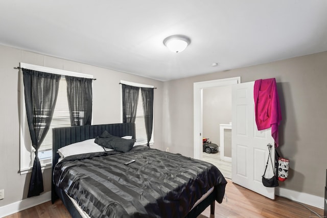 bedroom with multiple windows, baseboards, and wood finished floors