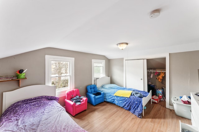 bedroom featuring wood finished floors, a closet, and vaulted ceiling