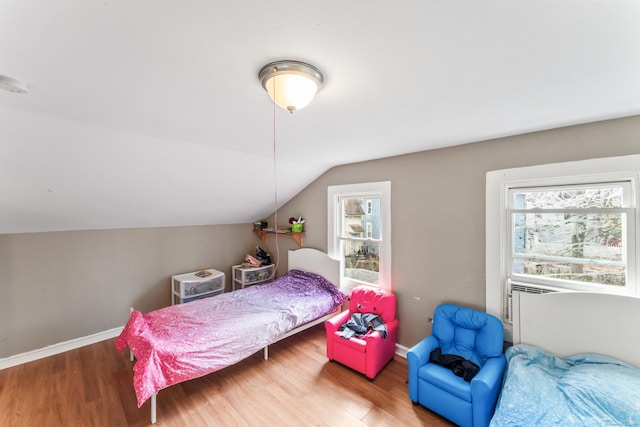 bedroom featuring wood finished floors, baseboards, multiple windows, and lofted ceiling