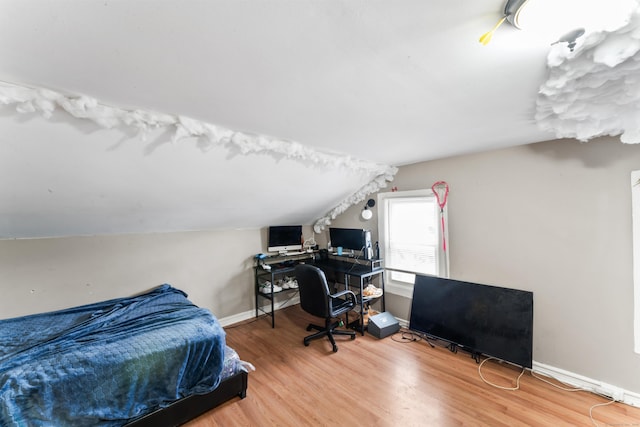 bedroom featuring wood finished floors, baseboards, and lofted ceiling