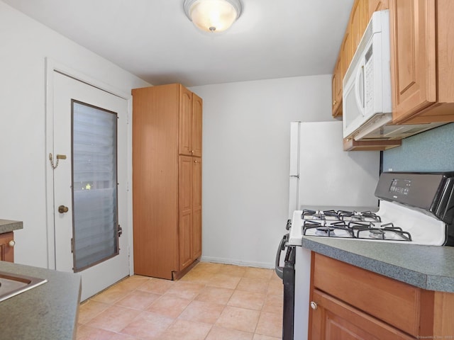 kitchen featuring white microwave, gas stove, and dark countertops