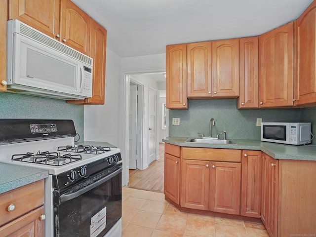 kitchen featuring a sink, range with gas cooktop, light tile patterned flooring, and white microwave